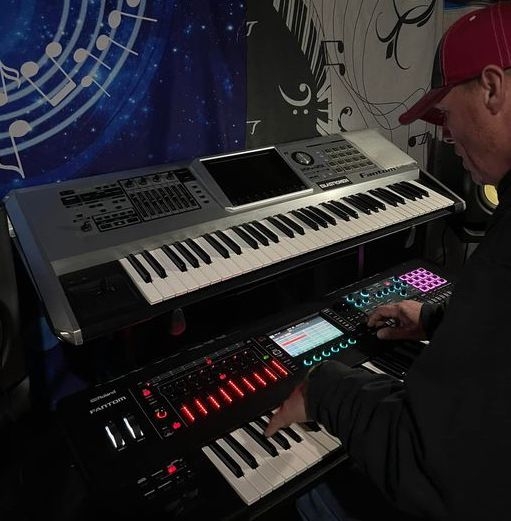 DJ Natural Nate® at dual Roland Fantom keyboards in the studio with music note backdrop